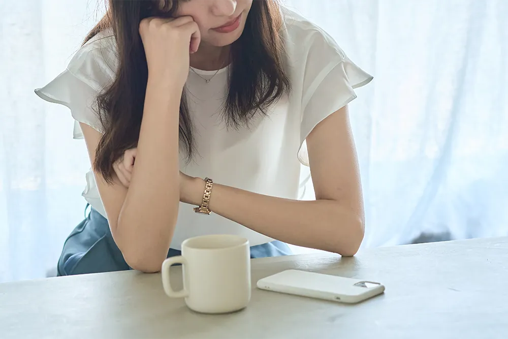 コーヒーを飲みながらため息をつく女性